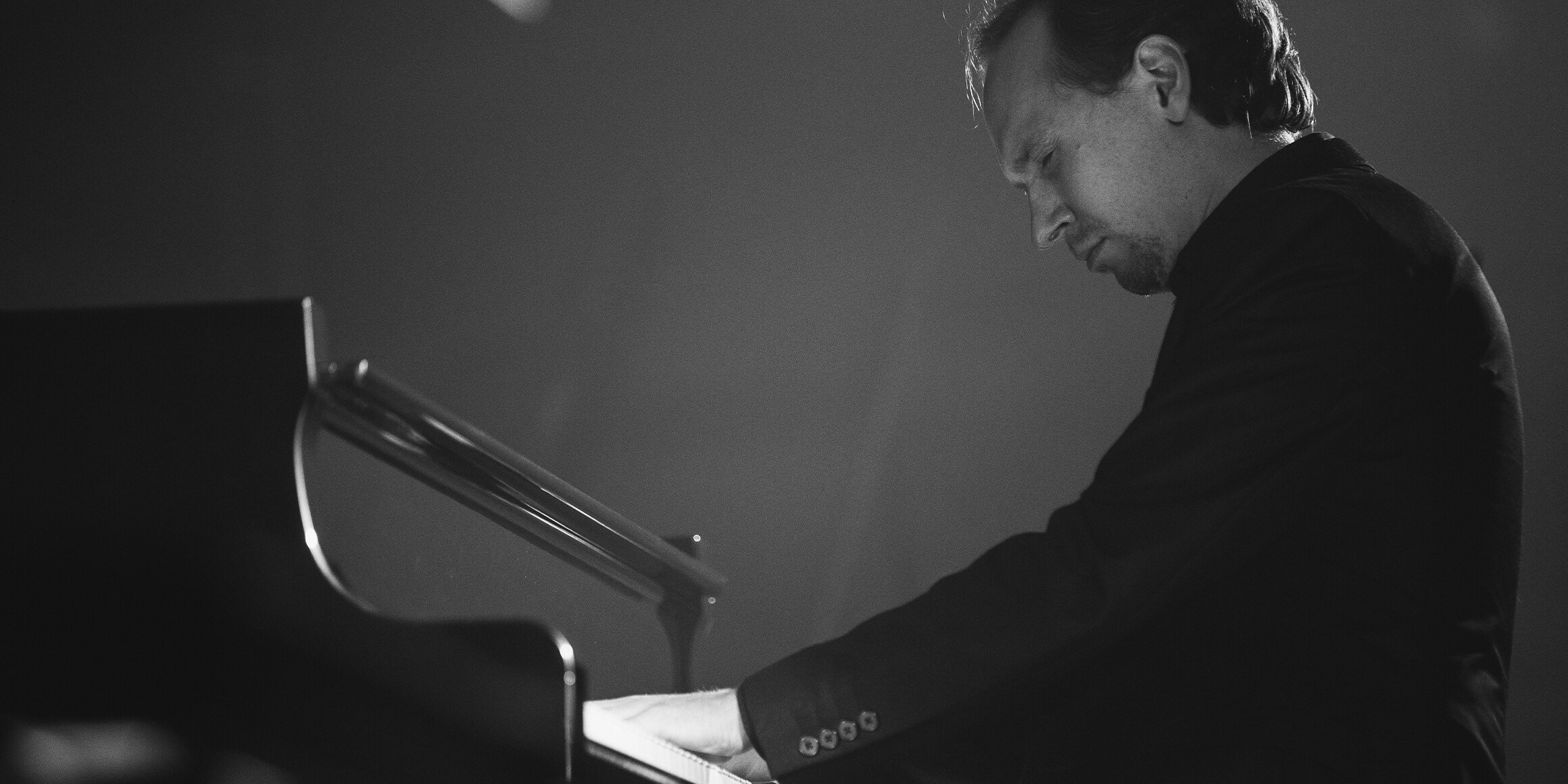 Composer Alexey Kurbatov playing the piano black and white