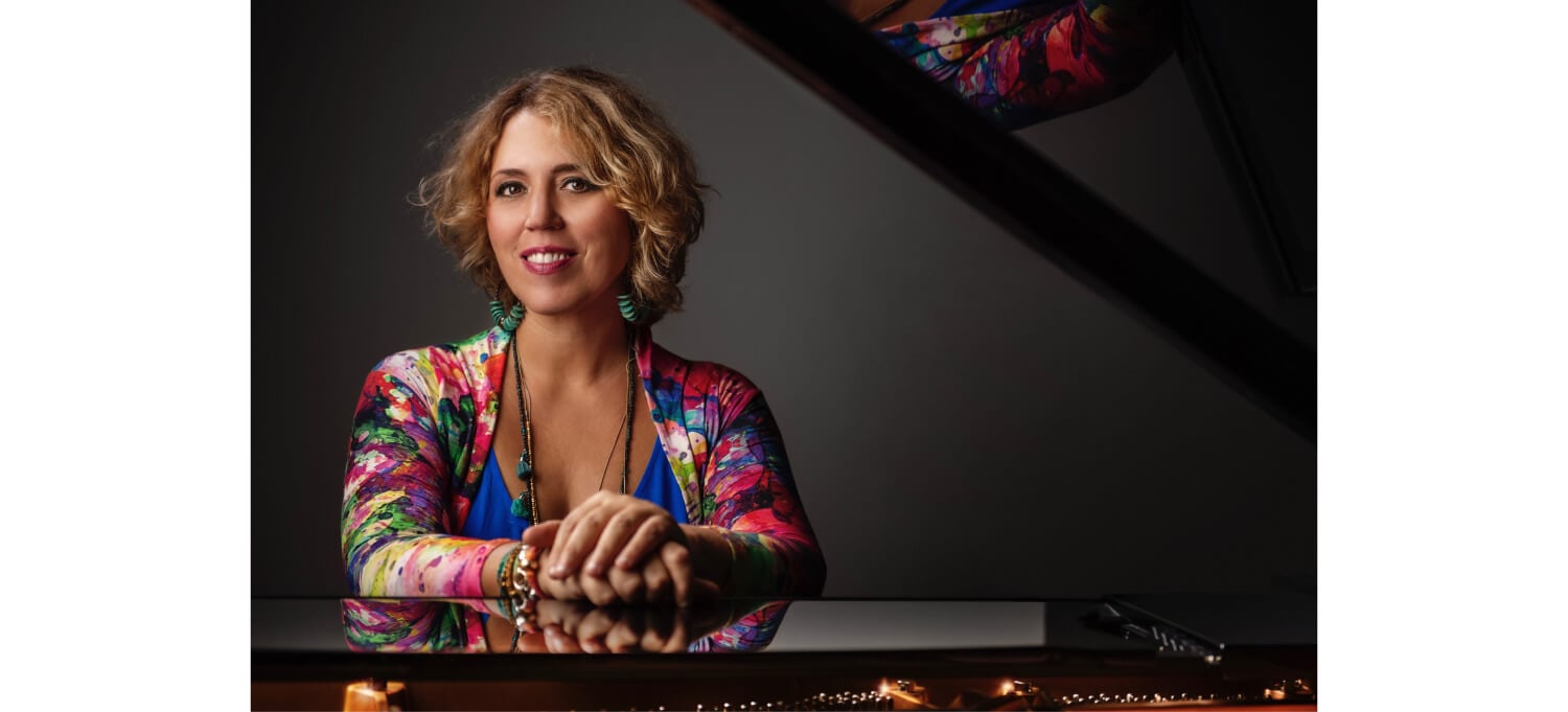 portrait of gabriela montero leaning on a piano